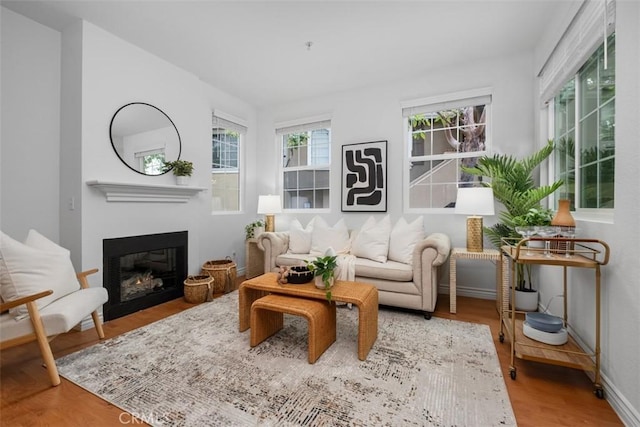 interior space with a glass covered fireplace, wood finished floors, and baseboards