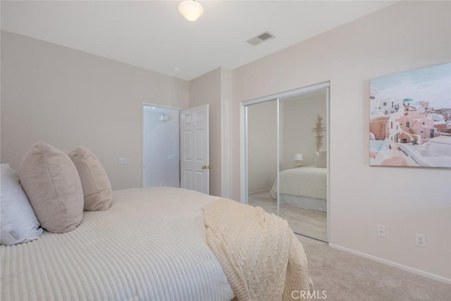 bedroom featuring baseboards, visible vents, light carpet, and a closet