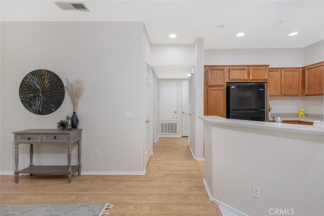 kitchen featuring freestanding refrigerator, light countertops, light wood-type flooring, baseboards, and visible vents