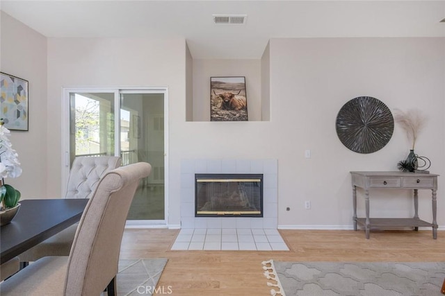 dining area with a fireplace, wood finished floors, visible vents, and baseboards