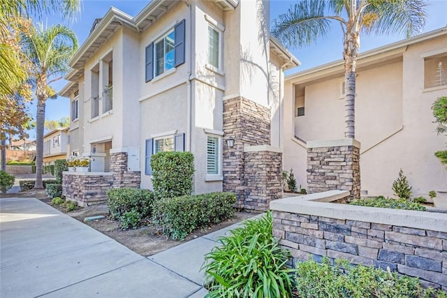 view of property exterior with stucco siding and stone siding
