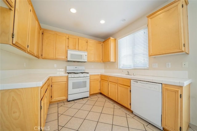 kitchen featuring light tile patterned floors, a sink, light brown cabinets, recessed lighting, and white appliances