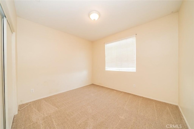 unfurnished room with baseboards and light carpet