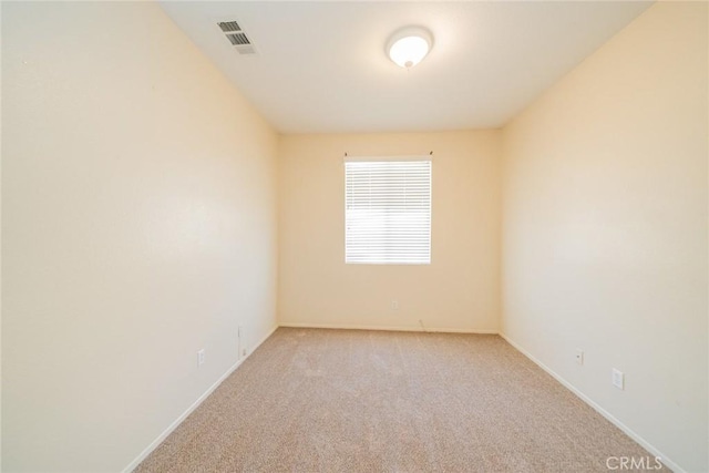 spare room featuring baseboards, light colored carpet, and visible vents