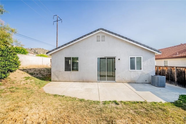 rear view of house featuring central AC unit, a fenced backyard, a yard, a patio, and stucco siding