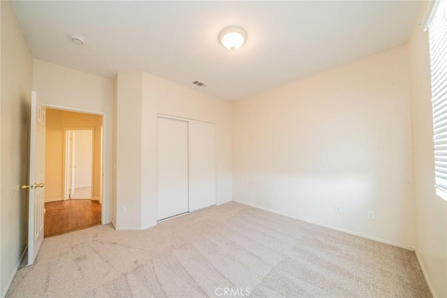 unfurnished bedroom featuring multiple windows, visible vents, baseboards, a closet, and carpet flooring