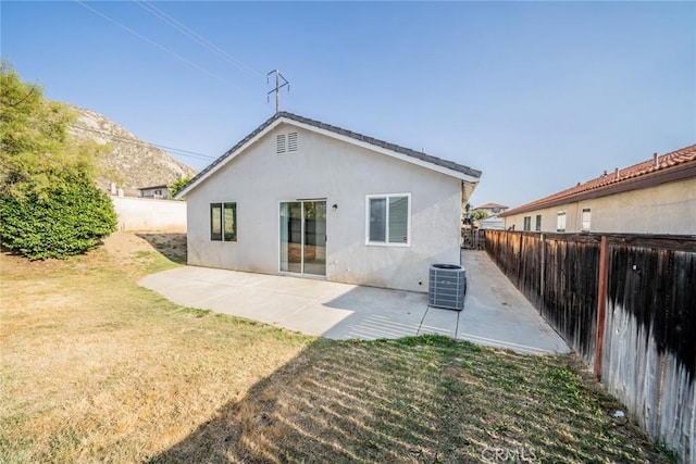 rear view of house with a fenced backyard, stucco siding, a patio area, central air condition unit, and a yard