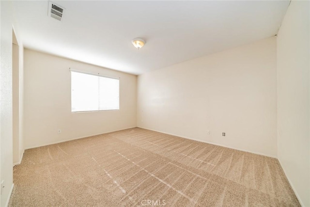 spare room featuring baseboards, visible vents, and carpet