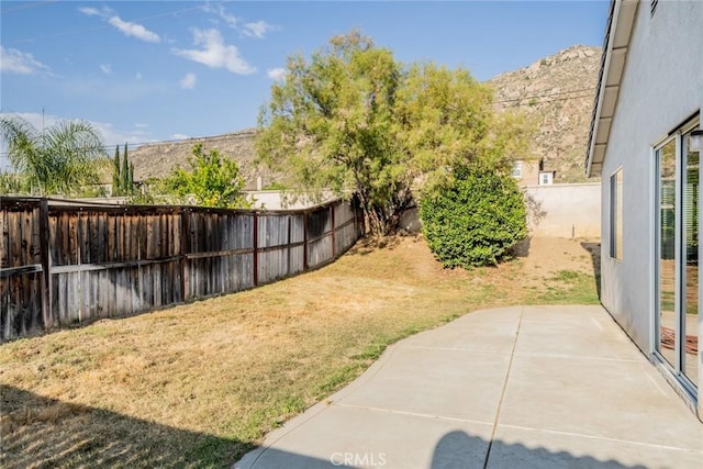 view of yard with a mountain view, a fenced backyard, and a patio area