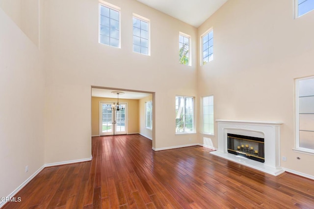 5018 Via Andrea, Newbury Park, CA 91320 - unfurnished living room with an inviting chandelier, a glass covered fireplace, baseboards, wood finished floors, and a towering ceiling