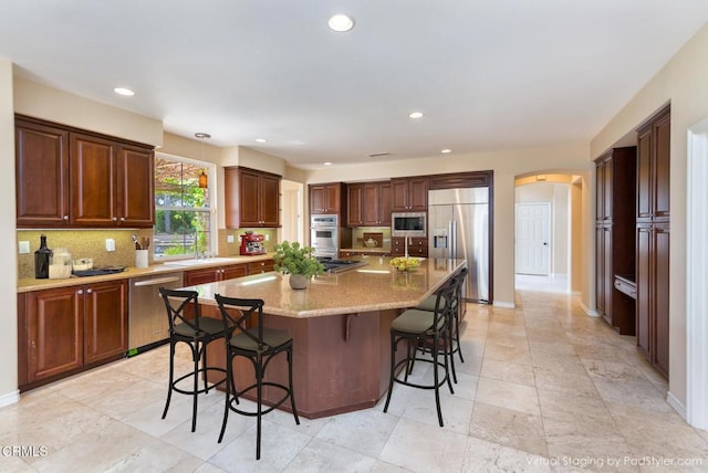 5018 Via Andrea, Newbury Park, CA 91320 - kitchen featuring built in appliances, a kitchen breakfast bar, backsplash, and arched walkways