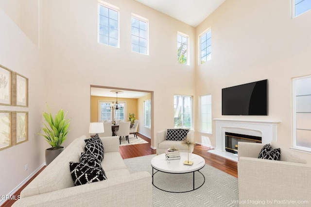 5018 Via Andrea, Newbury Park, CA 91320 - living area featuring wood finished floors, baseboards, a glass covered fireplace, an inviting chandelier, and a high ceiling
