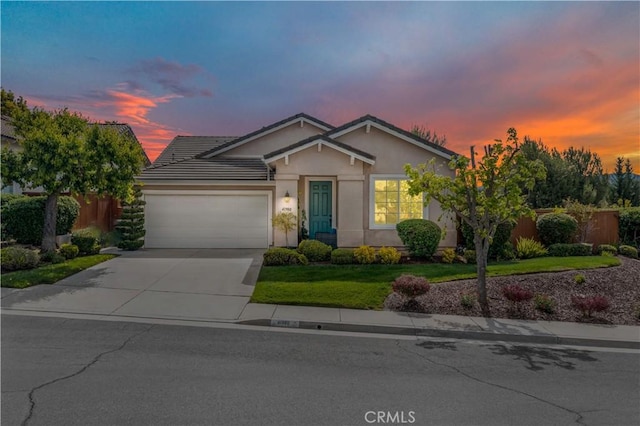 ranch-style home featuring driveway, fence, a front lawn, an attached garage, and stucco siding