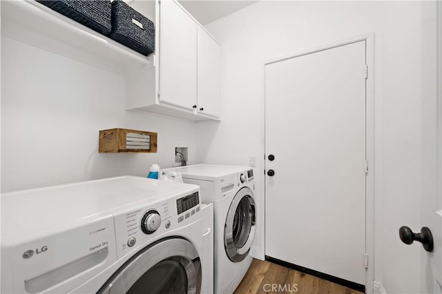 clothes washing area featuring light wood-style flooring, cabinet space, and washer and clothes dryer