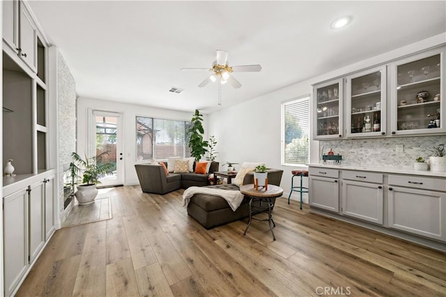 living area with a ceiling fan, recessed lighting, wood finished floors, and visible vents