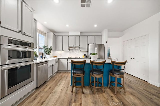 kitchen with gray cabinets, visible vents, appliances with stainless steel finishes, a sink, and light countertops