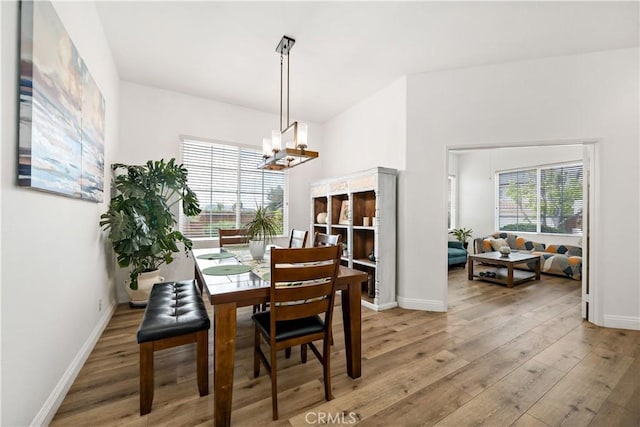 dining room featuring light wood-type flooring, baseboards, and a chandelier