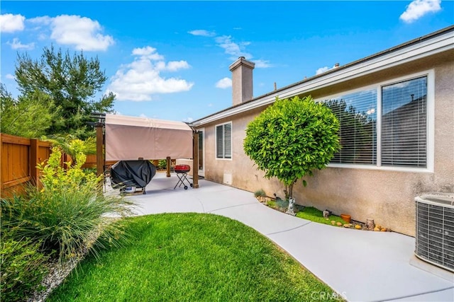 rear view of property with fence, stucco siding, a patio area, central air condition unit, and a yard