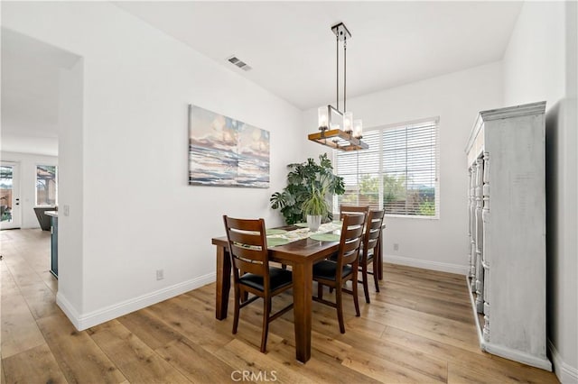 dining area featuring baseboards, visible vents, an inviting chandelier, and light wood-style flooring