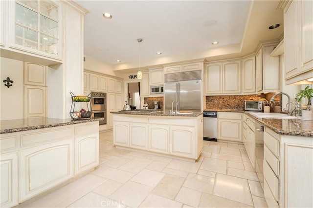 12 Santa Barbara Pl, Laguna Niguel, CA 92677 - kitchen featuring a sink, decorative backsplash, built in appliances, cream cabinetry, and dark stone countertops