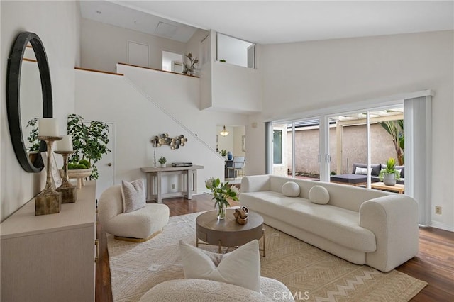 living room with stairway, a towering ceiling, and wood finished floors