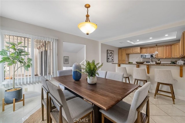 dining room featuring baseboards, recessed lighting, light tile patterned flooring, and a tray ceiling