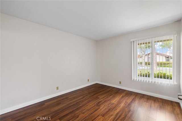 empty room featuring dark wood-style floors and baseboards