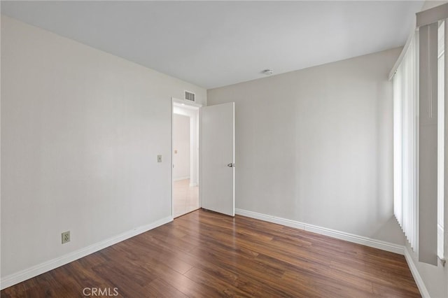 empty room with visible vents, wood finished floors, and baseboards