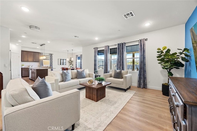 living room featuring recessed lighting, baseboards, visible vents, and light wood-type flooring