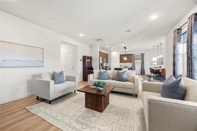 living room featuring recessed lighting, baseboards, visible vents, and light wood-type flooring