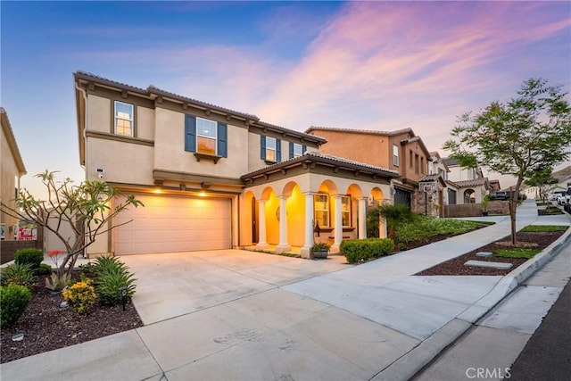 mediterranean / spanish-style home with an attached garage, driveway, and stucco siding