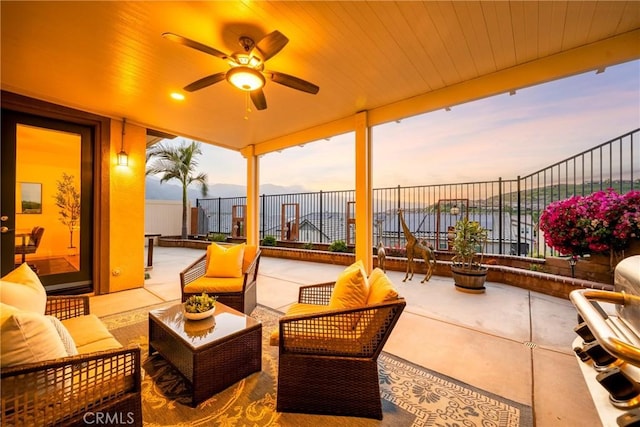 patio terrace at dusk with a fenced backyard, ceiling fan, and outdoor lounge area