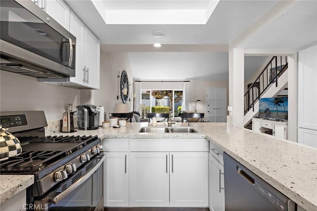133 Morristown Ln, Costa Mesa, CA 92626 - kitchen with stainless steel appliances, light stone counters, a sink, white cabinets, and a tray ceiling