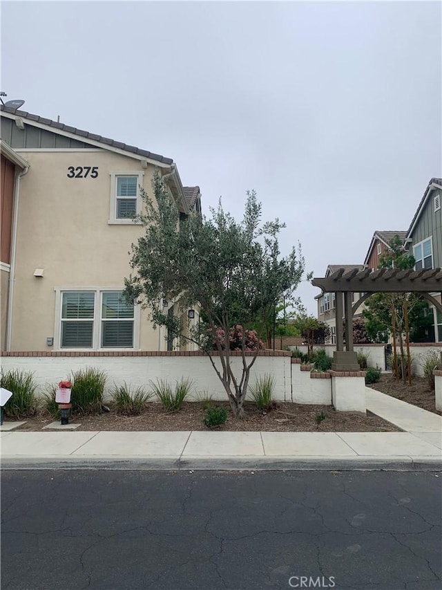 view of side of property with a pergola and stucco siding
