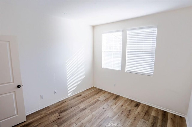 empty room featuring baseboards and light wood-type flooring