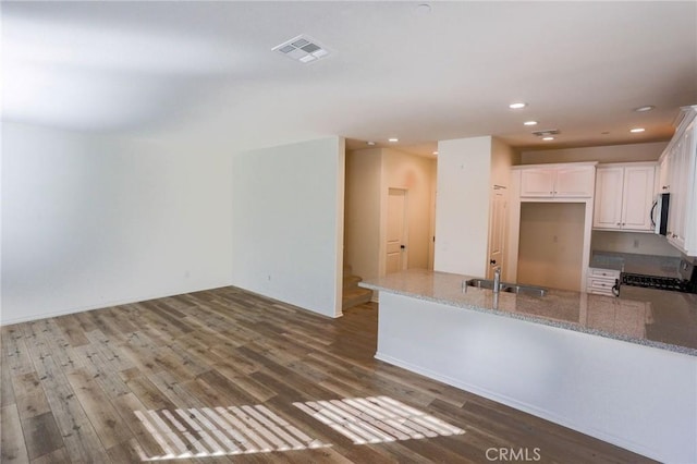 kitchen with light stone counters, a sink, white cabinets, appliances with stainless steel finishes, and visible vents