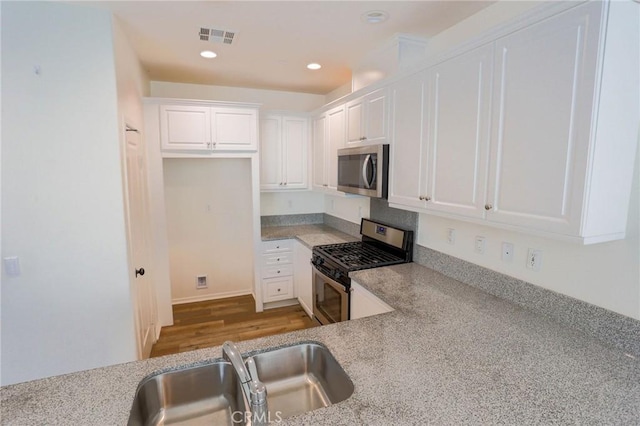 kitchen with recessed lighting, visible vents, a sink, appliances with stainless steel finishes, and white cabinetry
