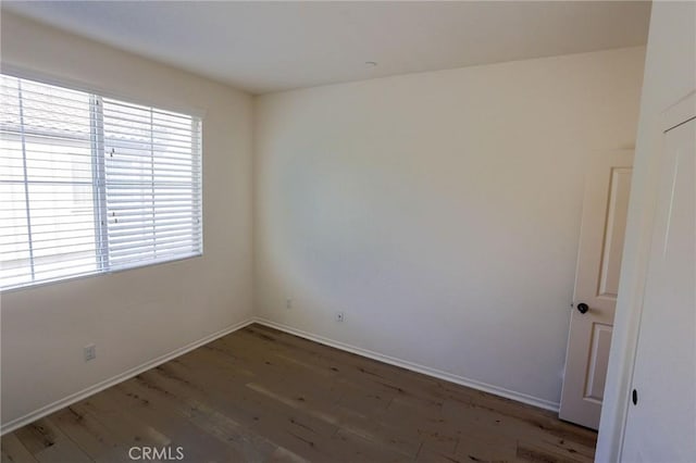 spare room featuring wood finished floors and baseboards
