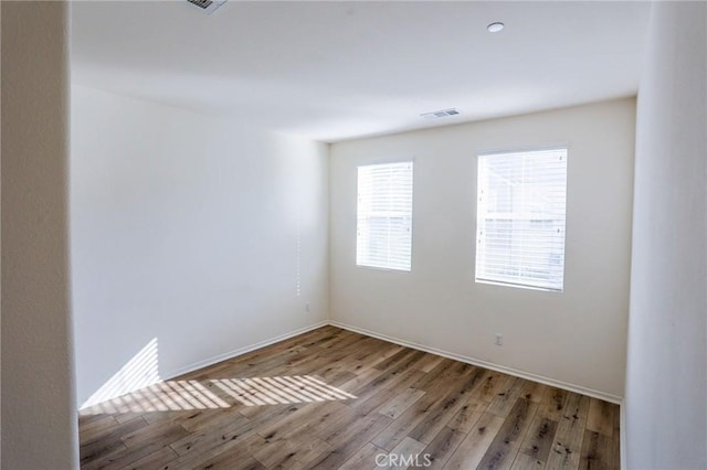 spare room featuring baseboards, light wood-style flooring, and visible vents