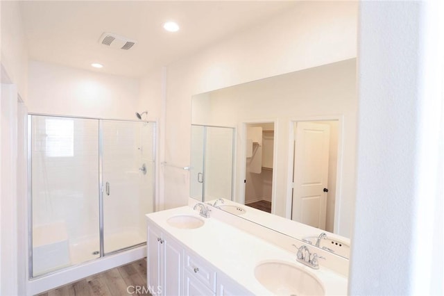 bathroom with a spacious closet, a shower stall, visible vents, and a sink