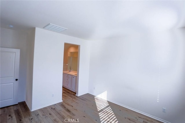 spare room with light wood-style floors, visible vents, and baseboards