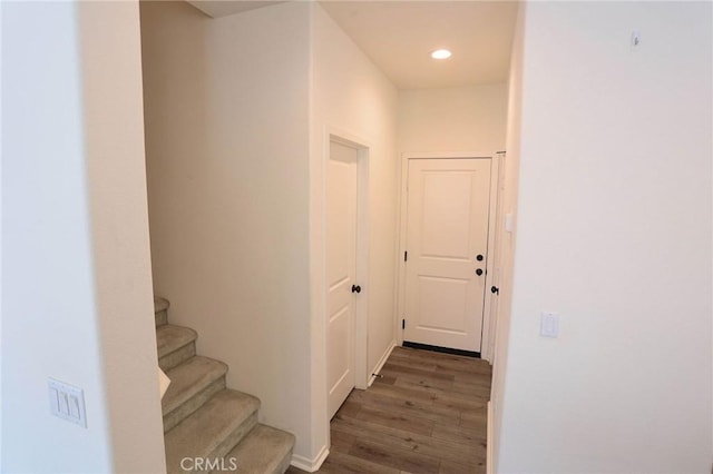 hall featuring wood finished floors, recessed lighting, and stairs