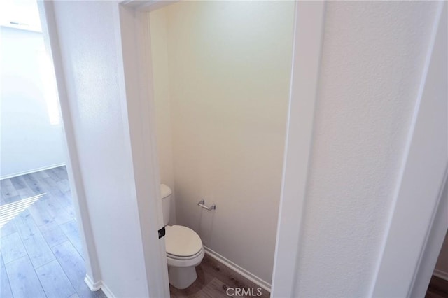bathroom with toilet, wood finished floors, and baseboards