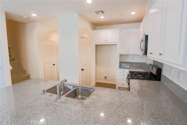 kitchen featuring light stone counters, a sink, stainless steel appliances, white cabinetry, and visible vents