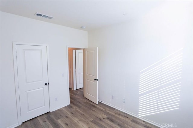 unfurnished bedroom featuring baseboards, wood finished floors, and visible vents