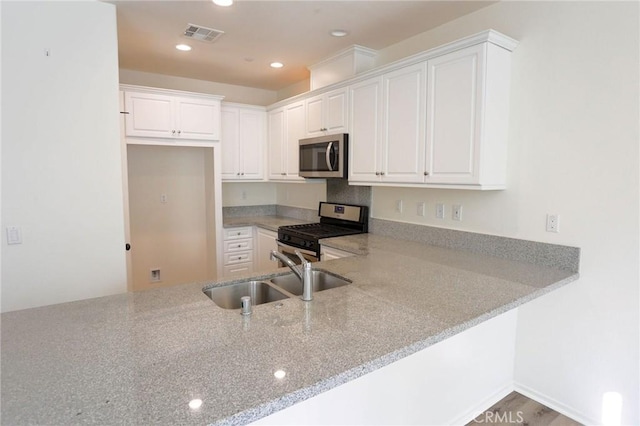 kitchen featuring light stone countertops, appliances with stainless steel finishes, white cabinetry, and a sink
