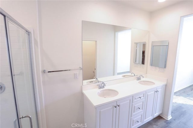 full bath featuring a sink, a shower stall, and double vanity