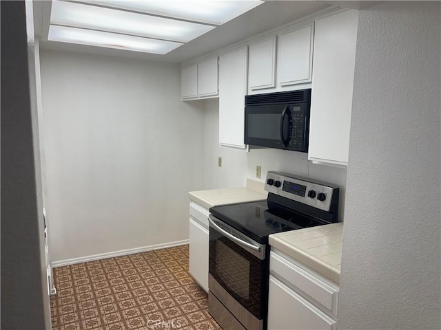600 W 9th St Unit 902, Los Angeles, CA 90015 - kitchen with stainless steel range with electric stovetop, black microwave, tile countertops, white cabinetry, and light flooring