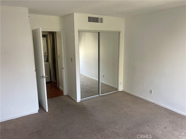600 W 9th St Unit 902, Los Angeles, CA 90015 - unfurnished bedroom with stacked washing machine and dryer, carpet, a closet, and a textured ceiling