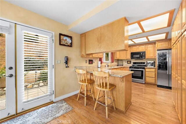 33435 Hubbard Rd, Acton, CA 93510 - kitchen with stainless steel appliances, a peninsula, light wood-type flooring, a kitchen breakfast bar, and plenty of natural light